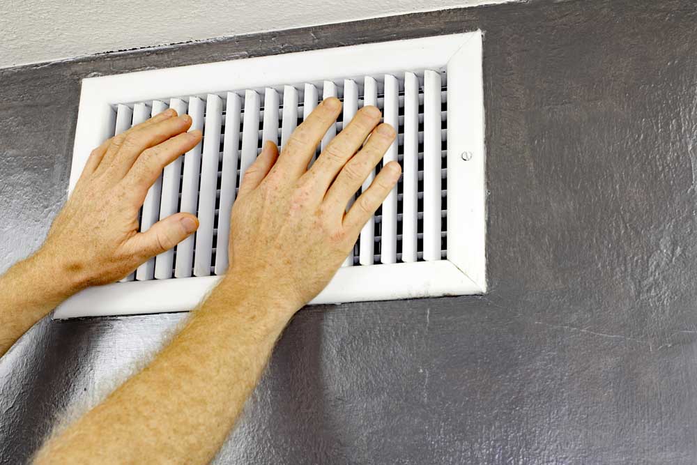 a person’s hand over air vents (checking for air flow)